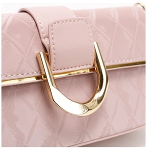 Gros-plan détail du sac à épaule élégant en cuir verni rose avec fermoir doré chic.