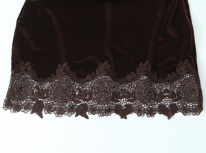 Détail de l'ourlet de la robe en velours marron foncé avec broderie de dentelle
