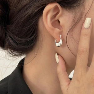 Close-up of minimalist S925 silver U-shaped hoop earring worn on an ear with polished finish