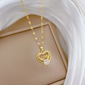 Makro-Detail des goldenen Herzanhängers mit LOVE-Gravur und Zirkonia-Inlay