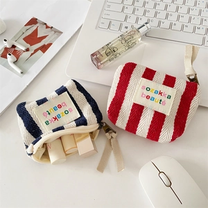 Detailed macro view of striped canvas makeup bags with embroidered labels and zippers