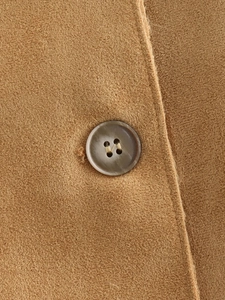 Close-up of brown suede fabric texture and dark brown round button detail on jacket