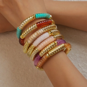 Gros plan de bracelets superposés en acrylique coloré et perles dorées en spirale