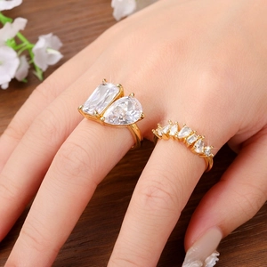 Close-up of gold double-stone ring and shimmering geometric diamond band on a hand