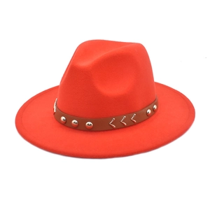 Detail of red wool felt fedora featuring brown leather band with silver metal rivets