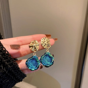 Close-up of vintage geometric earrings with gold metal and teal glitter resin pendants