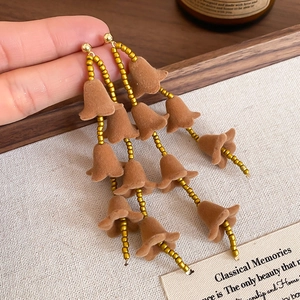 Détails de boucles d'oreilles fleurs marron floquées avec perles dorées et longs glands