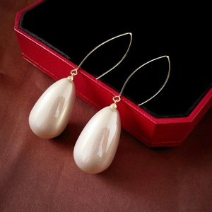 Detailed macro view of French style teardrop pearl earrings on a luxury velvet box