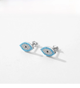Detailed view of silver evil eye stud earrings with turquoise stones and white crystals
