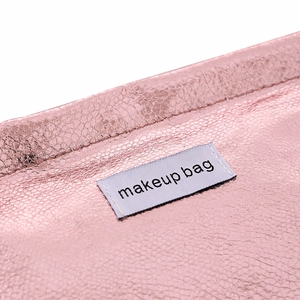 Close-up of pink metallic PU leather makeup bag with fine stitching and label