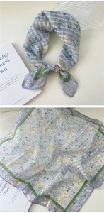 Detailed view of light blue floral linen scarf with green border and stripe pattern