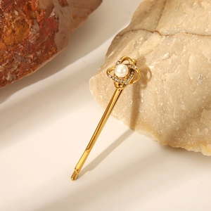 Dettaglio del fermaglio dorato per capelli con perla e strass scintillanti
