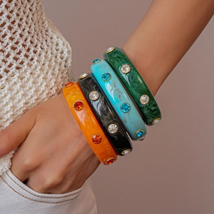 Detail of four colorful acrylic resin bangles with inlaid rhinestones on wrist