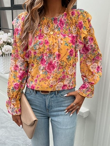 Detail of yellow long sleeve shirt featuring pink and blue floral print with pleated texture