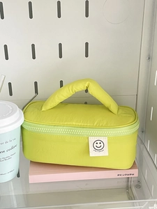 Detailed view of green padded cosmetics bag with smile patch and soft top handle