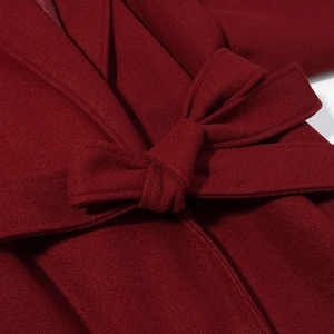 Detail of red wool coat showing a stylish waist belt tied in a neat decorative bow
