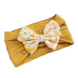 Yellow ribbed fabric baby headband with white floral bow detail on white background
