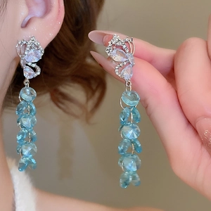 Détail de boucles d'oreilles papillon en cristal bleu avec strass brillants sur modèle