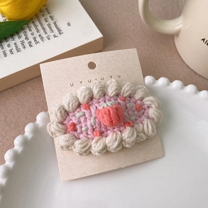 Détail d'une pince à cheveux crochetée avec une fraise 3D sur une base rose doux