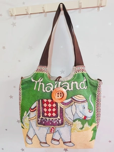 Detail der grünen Canvas-Tasche mit Elefanten-Stickerei, Thailand-Text und Holzknopf