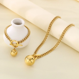 Dettaglio del set collana e bracciale a catena cubana dorata con sfera e chiusura a barra OT