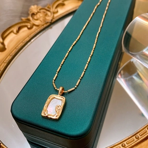 Detail of gold-plated square pendant with mother-of-pearl inlay on green jewelry box
