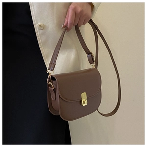Detailed view of a brown vintage saddle bag with gold metal buckle on a model