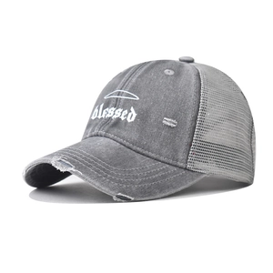 Detailed macro view of white gothic blessed embroidery on a distressed grey trucker hat
