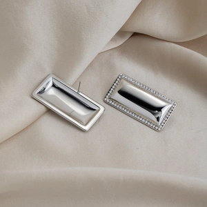 Detail of rectangular silver earrings with diamonds on elegant beige silk fabric