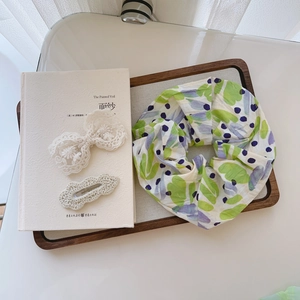 Floral fabric scrunchie with lace bow and crochet hair clips on a wooden tray