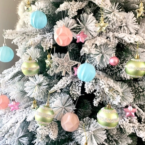 Detailed view of colorful assorted Christmas tree ornaments on a white flocked tree branch