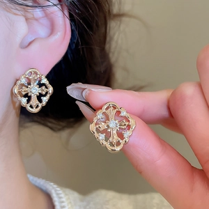 Macro shot of gold cross earrings featuring zircon inlays and vintage hollow patterns