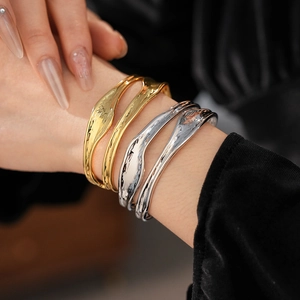 Macro view of layered irregular wave texture bracelets in gold and silver finish