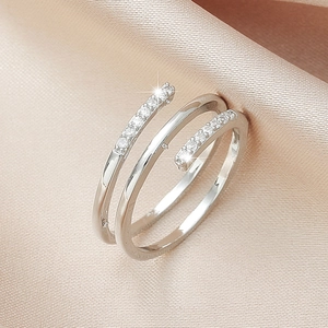 Close-up of double-layered silver spiral ring with white micro-diamonds on pink silk