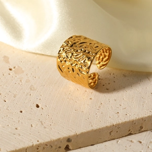 Lava textured gold wide open ring displayed on stone base with silk background