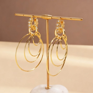 Macro detail of gold layered geometric hoop earrings with sparkling rhinestones