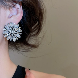 Close-up of luxury flower stud earrings with sparkling crystals on a female model