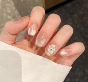 Macro view of champagne cat-eye press-on nails with 3D floral accents and rhinestones