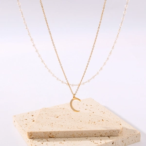 Double-layer necklace with white pearls, gold chain, and crescent moon pendant with crystals