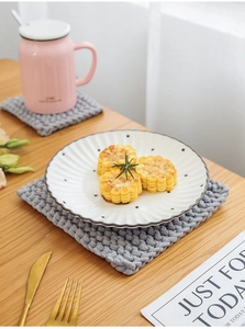 Detail of grey thick woven heat-resistant placemat and coaster on wooden table