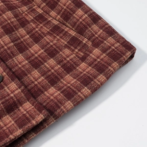 Detail of red and brown plaid wool coat showing fabric texture and button stitching