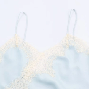 Detail of light blue satin camisole featuring delicate white eyelash lace trim and silk texture
