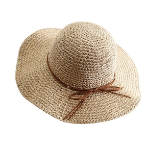 Women's foldable wide brim straw sun hat with brown ribbon bow on a white background