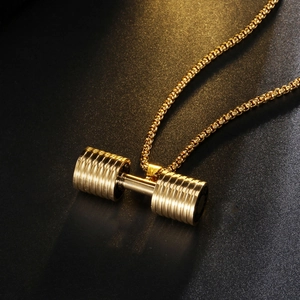 Close-up of golden dumbbell pendant necklace with metallic texture and warm lighting