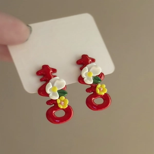 Detail view of red Xi character earrings with small white flower decorations