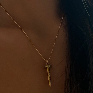 Detail of 18k gold plated screw-shaped pendant necklace with zircon on a female model
