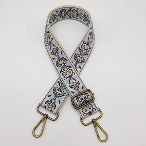 Close-up of wide embroidered bag strap in blue and brown with antique bronze metal buckles