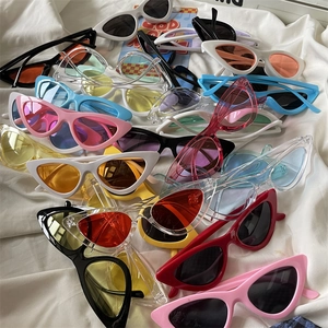 Collection of colorful cat-eye sunglasses in pink white and blue on a textured fabric