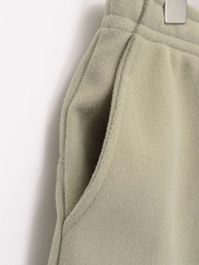 Close-up of soft light olive green fleece joggers with side pocket and fabric texture