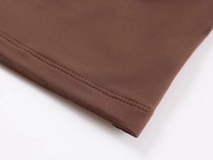 Macro shot of dark brown knitted fabric showing fine ribbed texture and double stitching